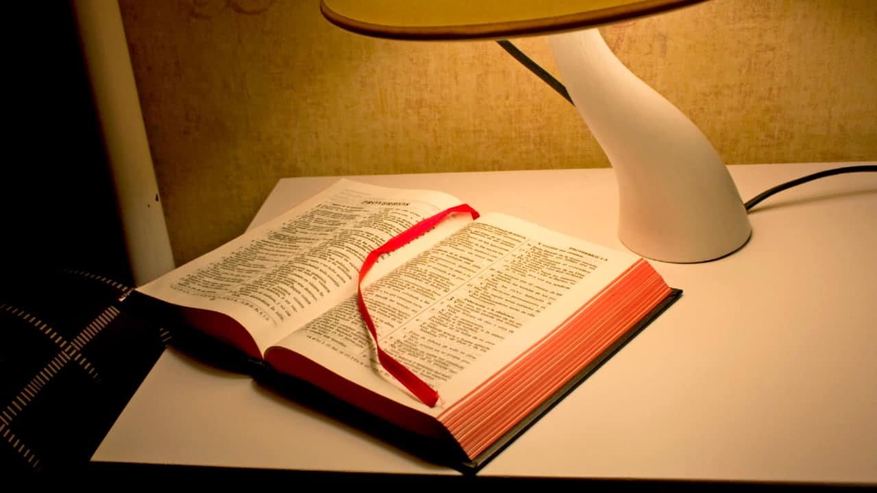 A bible on a table in a hotel room.