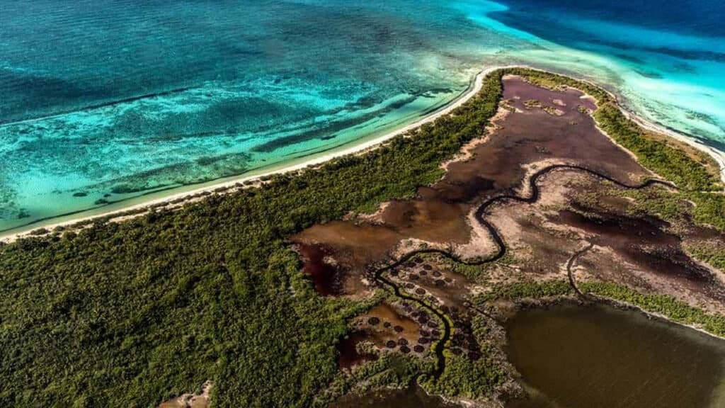 An aerial view of an island in the middle of the ocean, surrounded by beautiful turquoise waters.